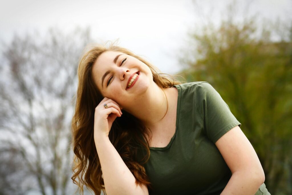 Femme assise, les yeux fermes et un léger sourire sur le visage, exprimant la paix intérieure et la gratitude.