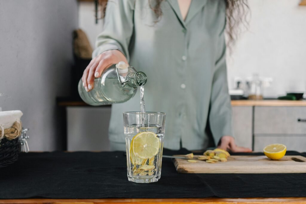 Femme remplissant un verre d'eau au réveil, geste simple et conscient pour bien commencer la journée.