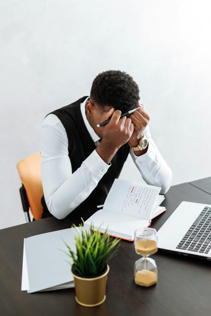 Un homme assis a son bureau, la tête dans les mains, illustrant un moment de stress intense.