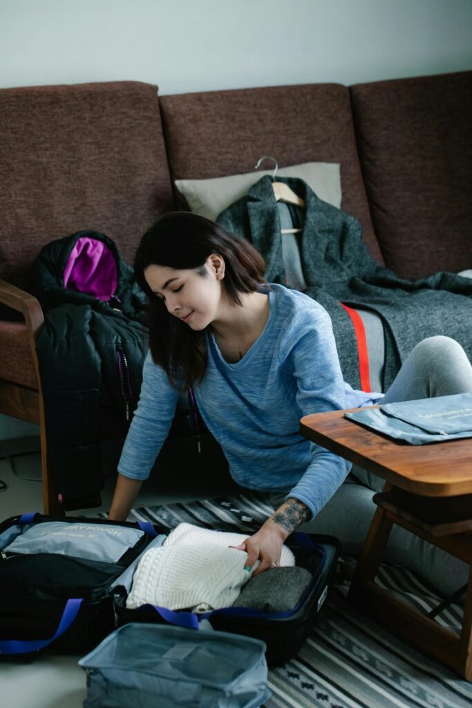 Femme assise au sol, en train de trier le contenu de son sac, concentrée sur l'essentiel.